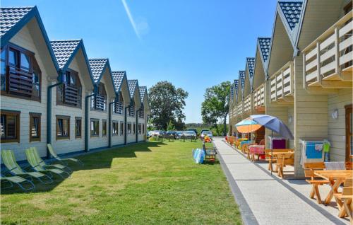 a row of buildings with tables and chairs on the grass at Cozy Home In Grzybowo With Kitchen in Grzybowo