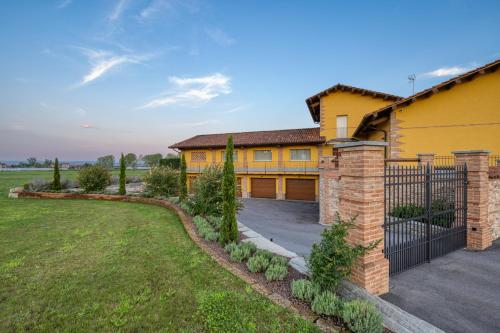 a yellow house with a fence and a yard at I Boschetti in Magliano Alpi
