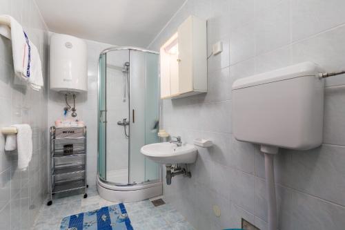 a white bathroom with a sink and a shower at Apartment Klenovica 5575c in Klenovica