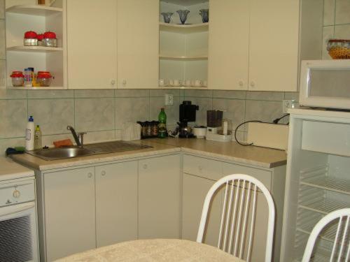 eine Küche mit weißen Schränken, einer Spüle und einer Mikrowelle in der Unterkunft Szigeti B&B in Bogács