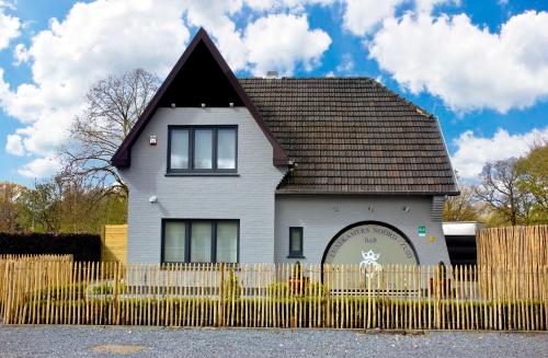 a white house with a fence in front of it at B&B Noord-Zuid in Zonhoven