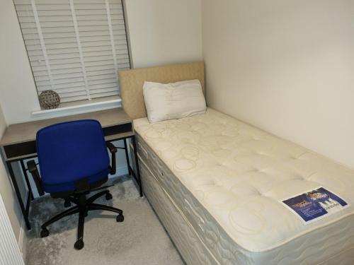 ein Bett und ein blauer Stuhl in einem Zimmer in der Unterkunft 26 Lindhurst Way West in Mansfield