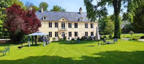 a large house with chairs and an umbrella in the yard at Château de Bellefontaine - Teritoria in Bayeux