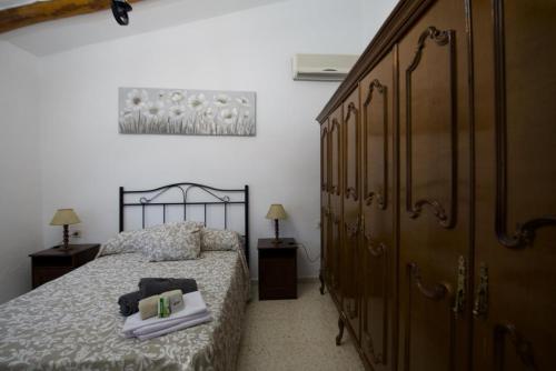 1 dormitorio con 1 cama y un gran armario de madera en CASA RURAL SANTA ELENA, en Cazalla de la Sierra