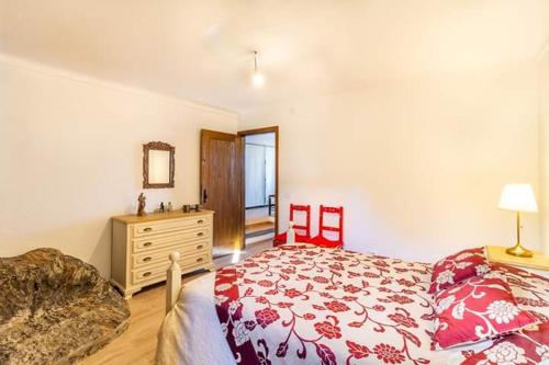 ein Schlafzimmer mit einem Bett, einer Kommode und zwei roten Stühlen in der Unterkunft Casa de São bento - Monsaraz in Monsaraz