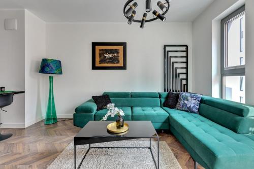 uma sala de estar com um sofá verde e uma mesa em Comfort Apartments Granaria em Gdansk