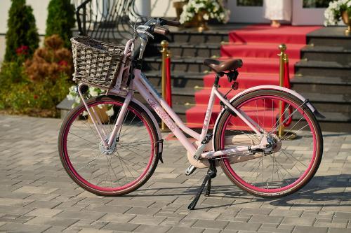 a bike with a basket parked on a sidewalk at La Rose Residence in Mikołajki