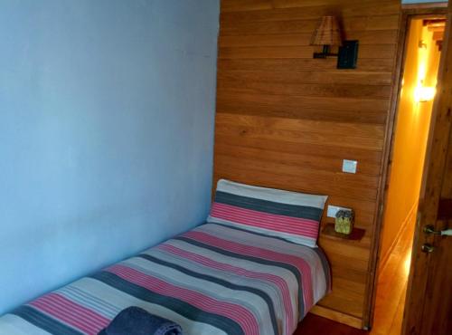 a small bed in a room with a striped blanket at Cal Puro in Castellnou de Seana