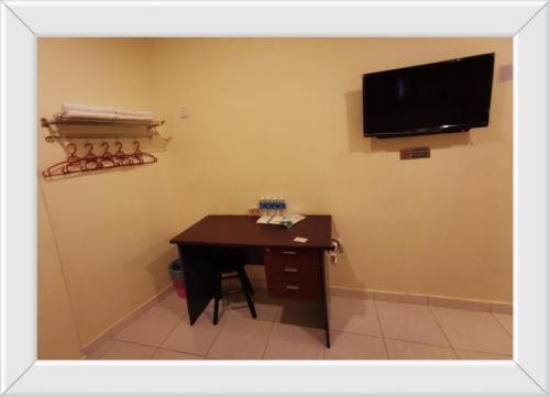 Habitación con escritorio y TV en la pared. en Hotel Bandar Baru Menglembu en Ipoh