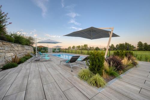 a patio with an umbrella and chairs and a pool at Appartamento I Boschetti in Magliano Alpi