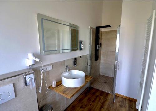 ein Badezimmer mit einem weißen Waschbecken und einer Dusche in der Unterkunft Sporthotel Dorum in Dorum