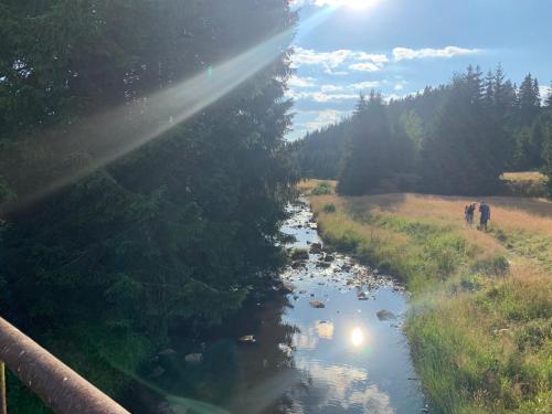 two people walking on a bridge over a river at Chalupa Magistrála in Horní Blatná