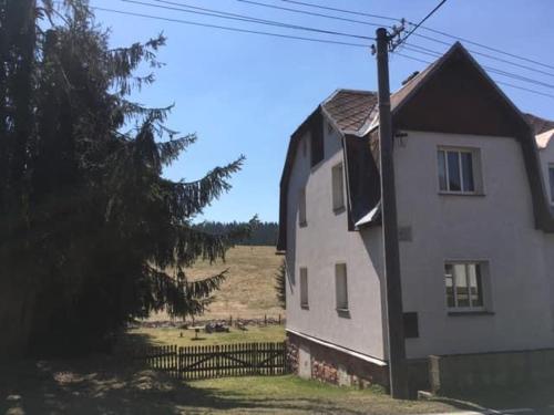 a white house with a fence next to a field at Chalupa Magistrála in Horní Blatná