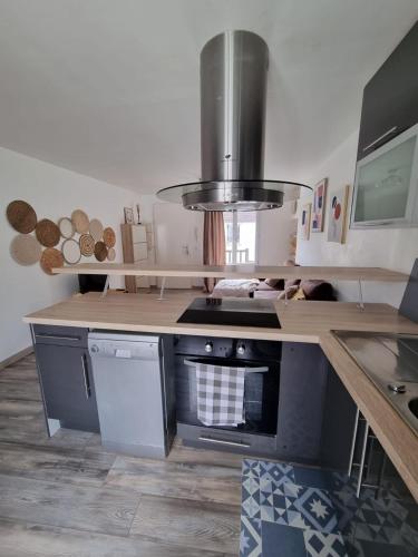 Il comprend une cuisine équipée d'une cuisinière. four supérieur à côté d'un comptoir dans l'établissement Duplex 40m2 cocooning cœur de ville avec parking, à Neauphle-le-Château