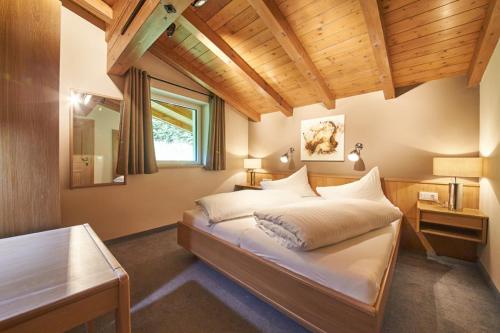 1 dormitorio con cama y techo de madera en Boutique Appartements en Saalbach Hinterglemm