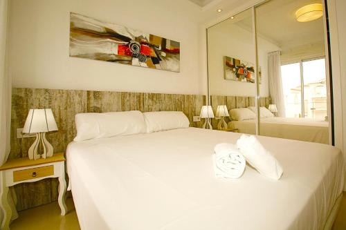 a bedroom with a large white bed and a mirror at Luxury bungalow Allegra 43 with AC and Pool in Ciudad Quesada