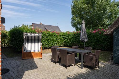 a patio with a table and an umbrella and chairs at Auster Hues in Midlum