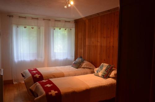クールマイヨールにあるChalet Svizzero Val Ferretのベッドルーム1室(ベッド2台、クロス付)