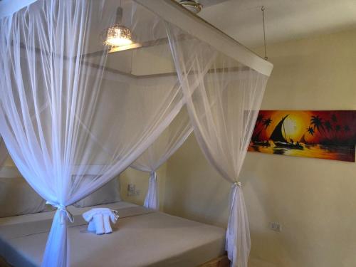 a bedroom with a bed with a white curtain at Zanzibar Tropical Sunset Boutique Hotel - Adults Only in Kiwengwa