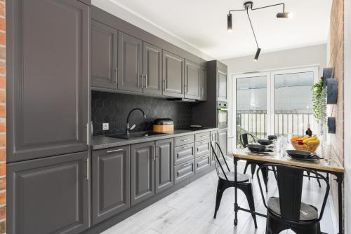 a kitchen with gray cabinets and a table with chairs at Family Apartment 62m - Sowia with GARAGE & BALCONY by Renters in Poznań