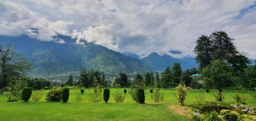 a green field with a mountain in the background at Anand Vardhan Resorts in Manāli