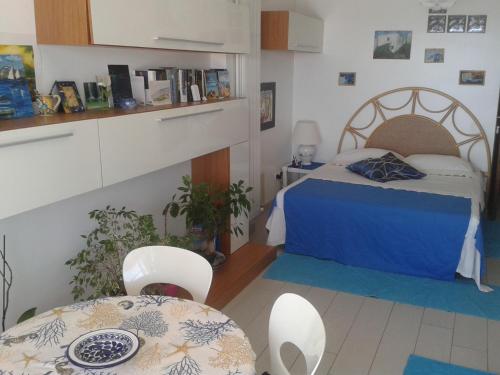 1 dormitorio con 1 cama, mesa y sillas en Limoni Sul Mare, en Torre Faro