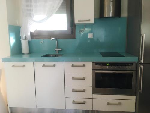a kitchen with white cabinets and a blue counter top at Aestas in Neos Marmaras