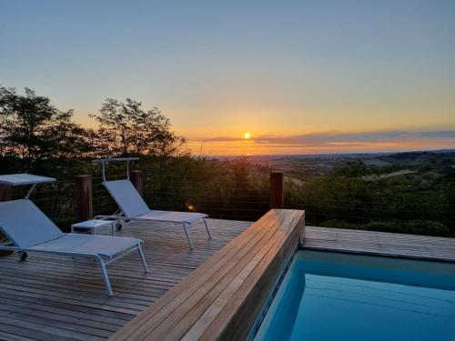 a deck with two chairs and a pool with the sunset at Resort Villa Paola in Longiano