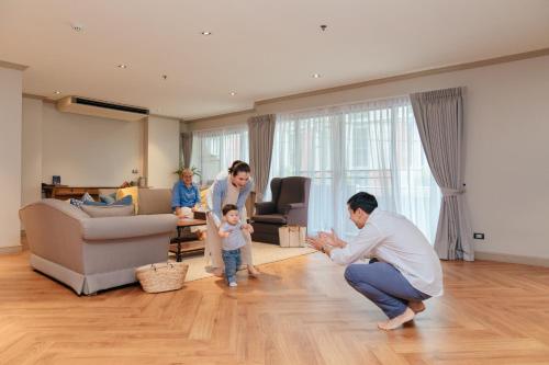 a family playing with a child in a living room at THEA Private Suites by TH District in Bangkok