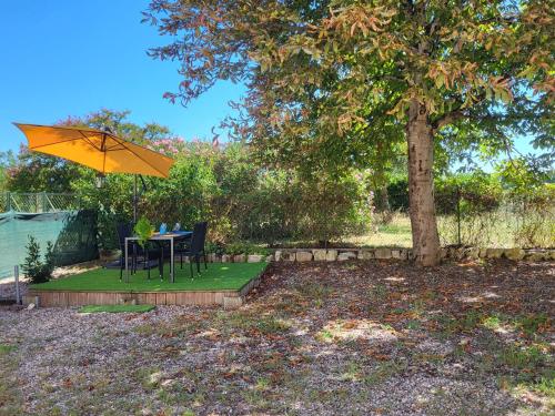 une table et des chaises sous un parapluie jaune placé sous un arbre dans l'établissement Maison chaleureuse avec exterieur près de la ville, à Lafox