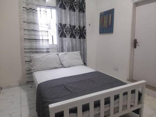 ein Schlafzimmer mit einem Bett in einem Zimmer mit einem Fenster in der Unterkunft Tapis Guest House in Brikama