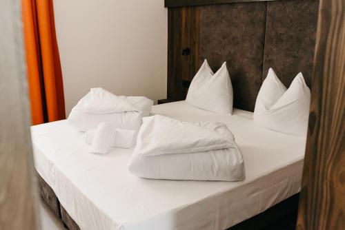 uma cama branca com almofadas brancas em Nepomuk rooms em Vipiteno