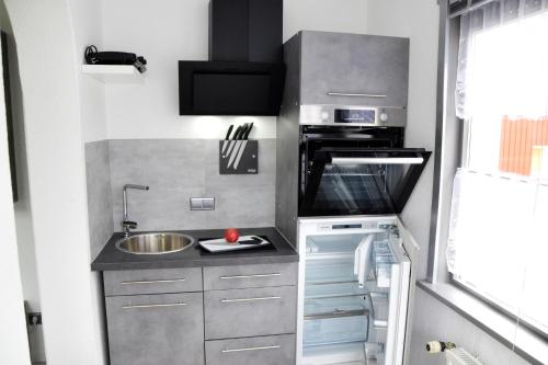 uma pequena cozinha com um lavatório e um fogão em FeWo Sonja em Sankt Andreasberg