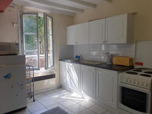a kitchen with white cabinets and a window at Saint Cyr du Bailleul - Maison in Saint-Cyr-du-Bailleul