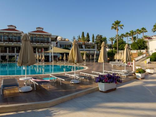 a swimming pool with chairs and umbrellas in a resort at AQI Hydros Club in Kemer