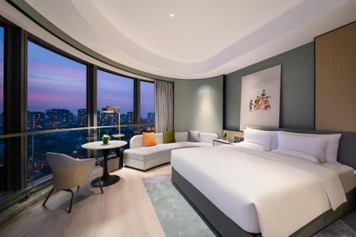 um quarto com uma cama branca e uma grande janela em Novotel Shanghai Caohejing em Xangai