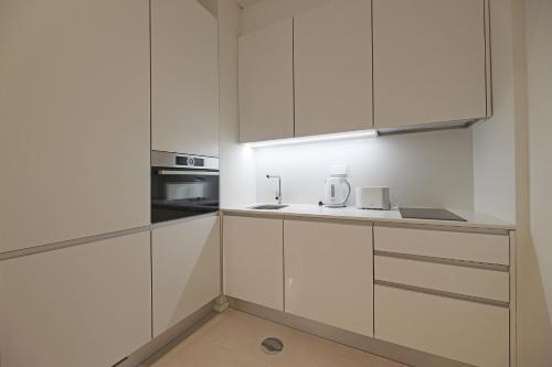 a white kitchen with white cabinets and a sink at FLH Gaia Homey Flat with Pateo II in Vila Nova de Gaia