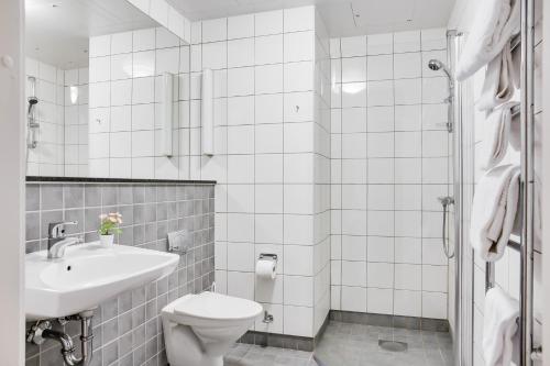 Baño blanco con lavabo y aseo en Forenom Aparthotel Lund, en Lund