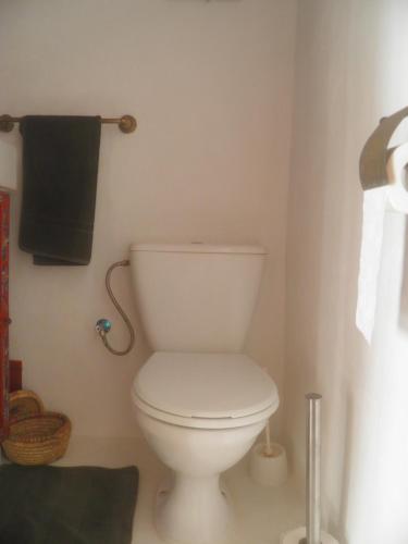 a bathroom with a white toilet and a black towel at La Maison des Artistes in Essaouira