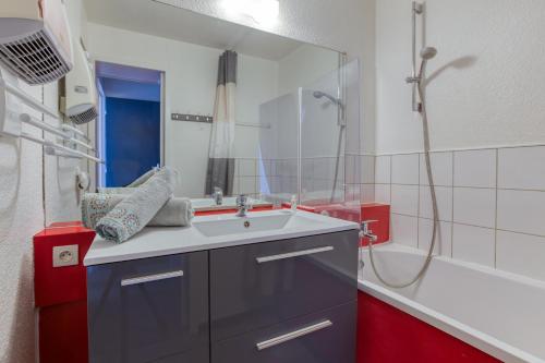 a bathroom with a sink and a shower with a mirror at L'Ancolie in Le Corbier