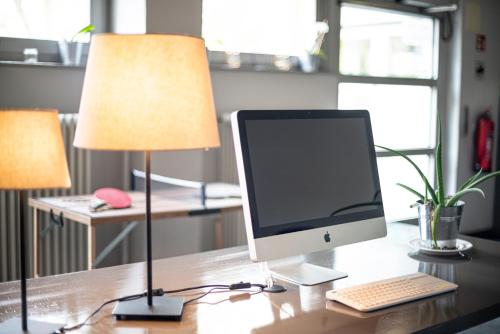 a computer monitor sitting on a desk with a lamp at BIG MAMA Berlin in Berlin