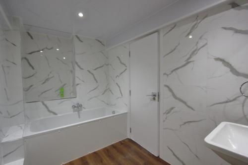 a bathroom with white marble walls and a sink at Lovely 2 Bed 2 Bath Flat & Parking by CozyNest in Reading