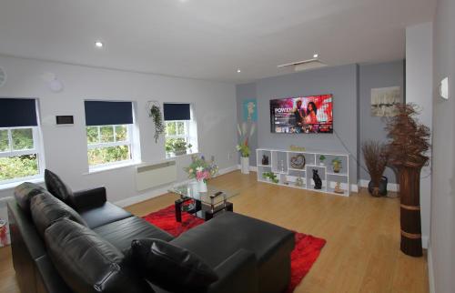 a living room with a black couch and a red rug at Lovely 2 Bed 2 Bath Flat & Parking by CozyNest in Reading