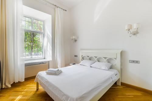 a white bedroom with a white bed and a window at KayKay Apartments in Odesa