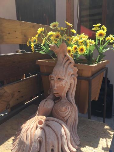 a wooden statue sitting next to a bench with flowers at Village Jazz in Chimankend