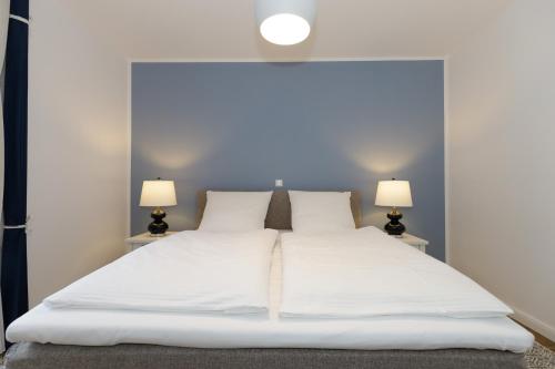 - une chambre avec un grand lit blanc et deux lampes dans l'établissement Villa Camenia, à Kühlungsborn