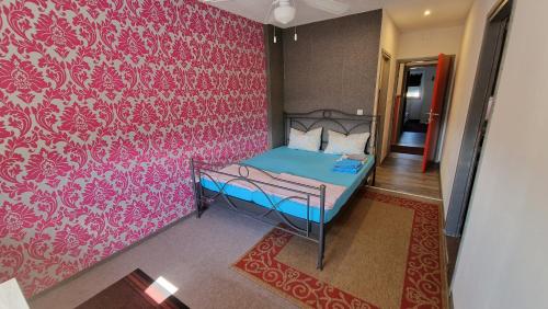 a bedroom with a bed with a pink wall at Neiras Apartments Blagaj in Blagaj