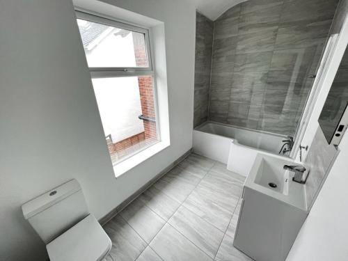 baño con aseo y lavabo y ventana en Dukes Place sleeps 10 comfortably en Wolverhampton