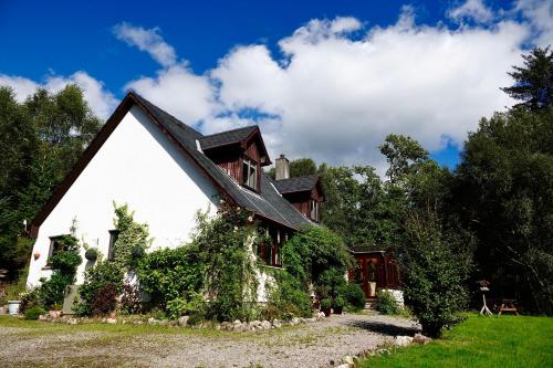 a house with ivy growing on the side of it at Tarmachan Cottage - West Highland Getaway in Fort William