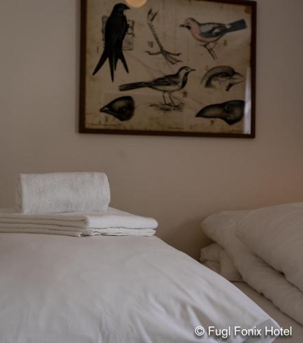 a white bed with a picture of birds on the wall at Fugl Fønix Hotel in Etnesjøen